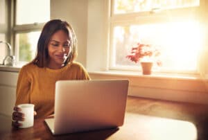 Woman having a cup of coffee while working on her laptop computer