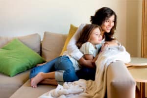 Mother and daughter sitting on the couch and looking out of a window