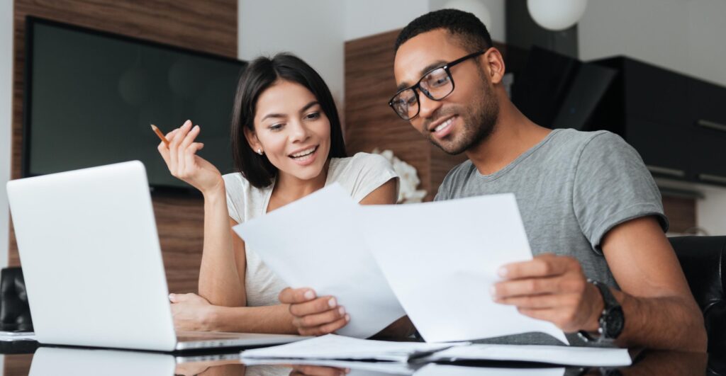 Couple looking at papers and using laptop computer