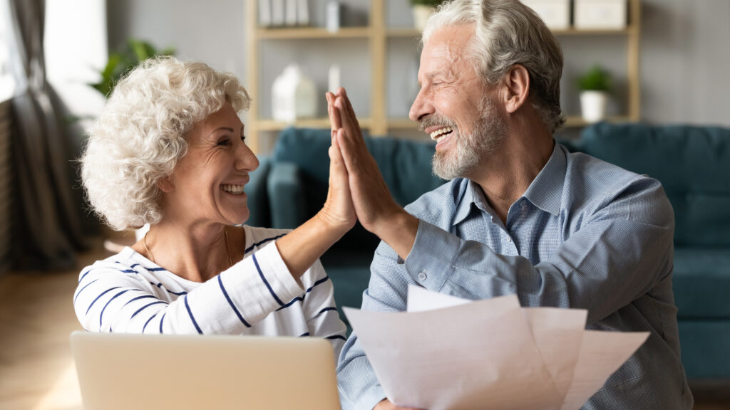 smiling woman and man holding financial documents high fiving