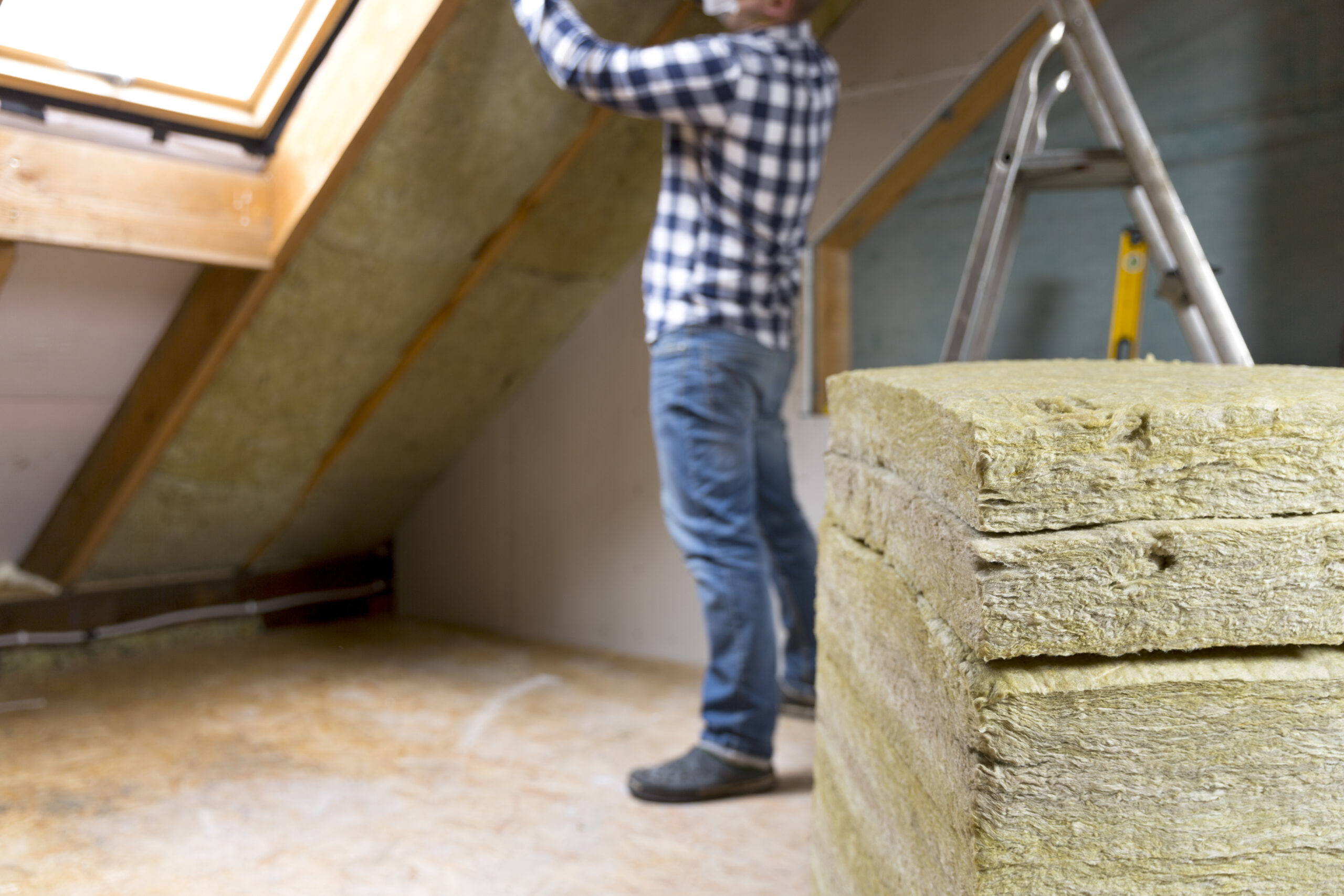 Man in an attic putting in insulation
