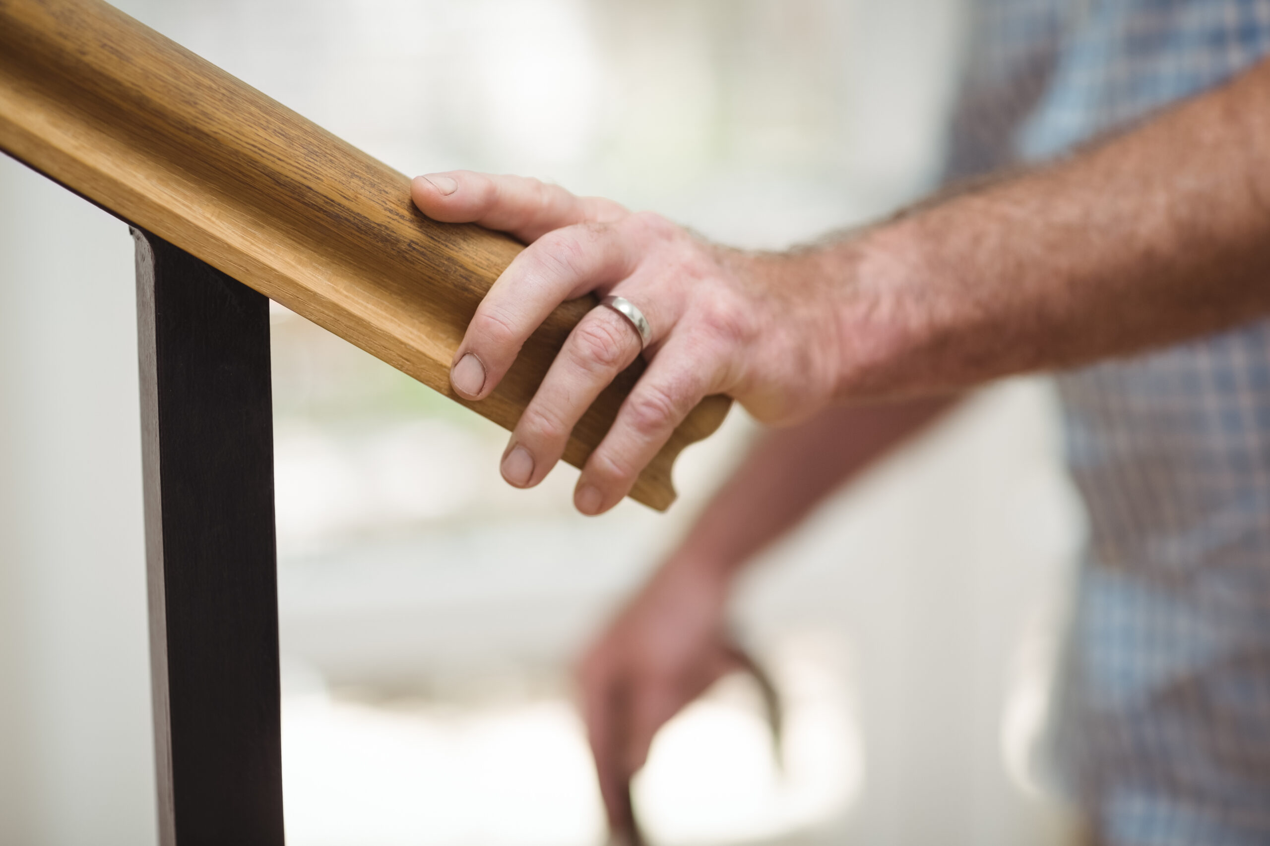 Mid section of senior man climbing upstairs with walking stick at home
